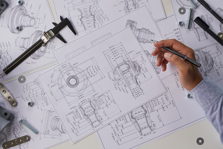 A hand of an engineer drawing IMP products, such as modular or mobile buildings