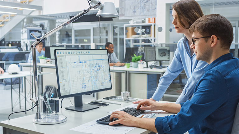 Two professional engineers discussing structual plans on a computer program in an office