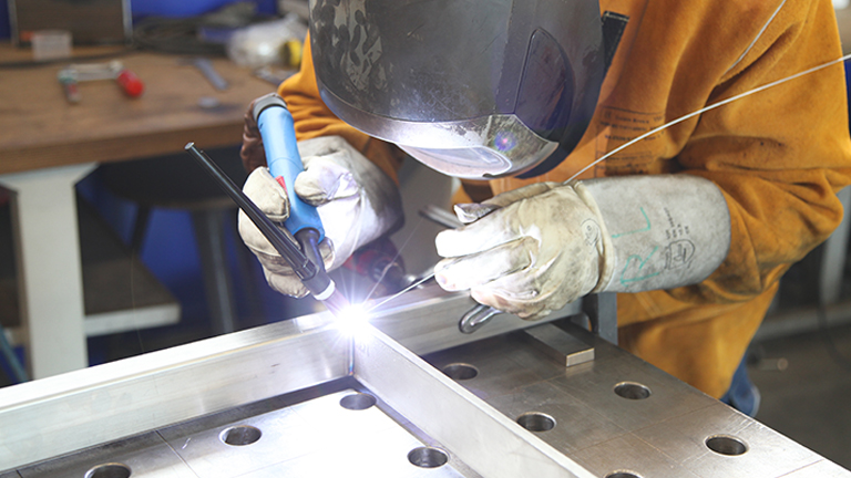 A professional fabrication welder welding together a product