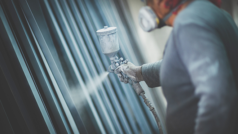 A professional painter using a spray gun to paint a structure