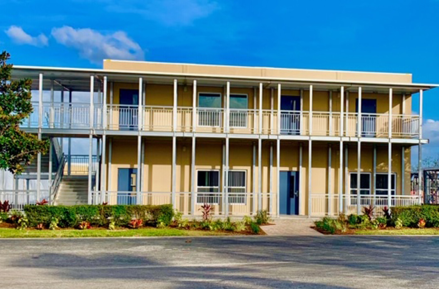 Structural building package with a white metal wrap around porch on the roadside with flower beds