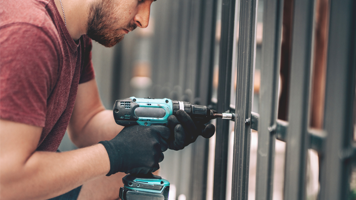 An assembly worker using an impact driver on a steel structure