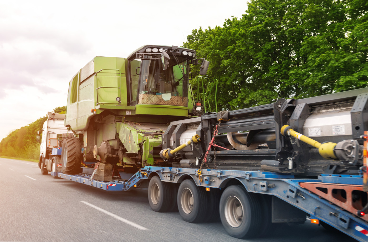 Combine harvester being hauled on a trailer by a semi truck