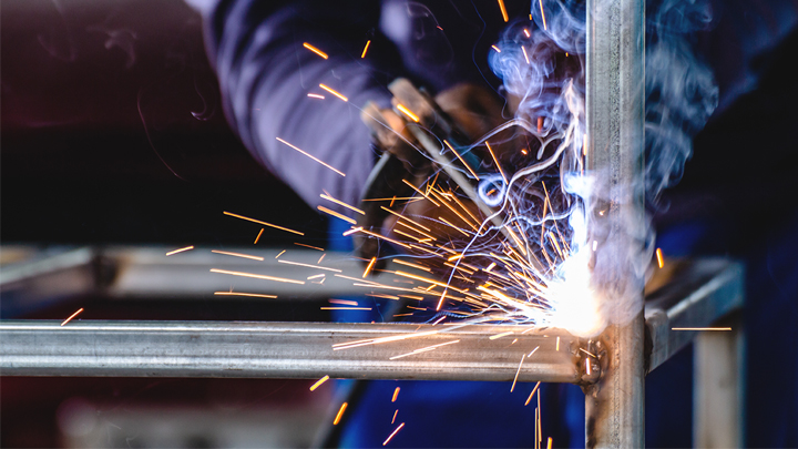 A closeup of professional fabrication welder welding together a structure