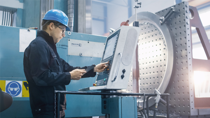 A professional machinist operating a computerized control panel