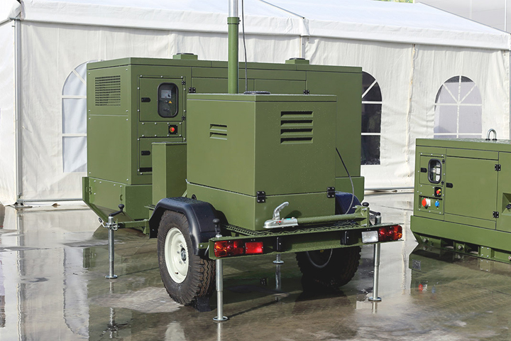 Green mobile military trailer in front of an outdoor event tent