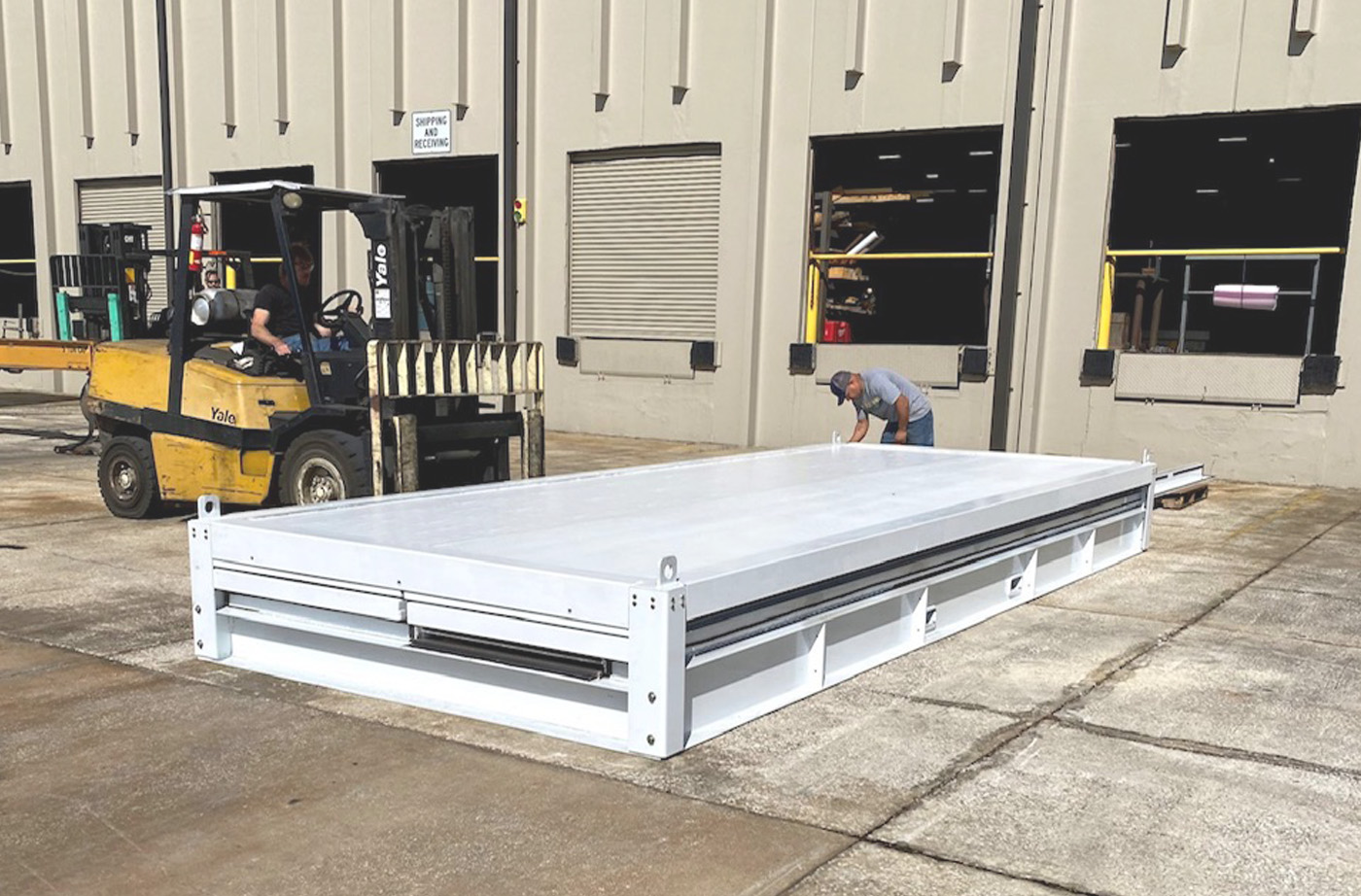 Two IMP employees preparing to assemble a rapid pod with a pallet fork attachment on a tractor