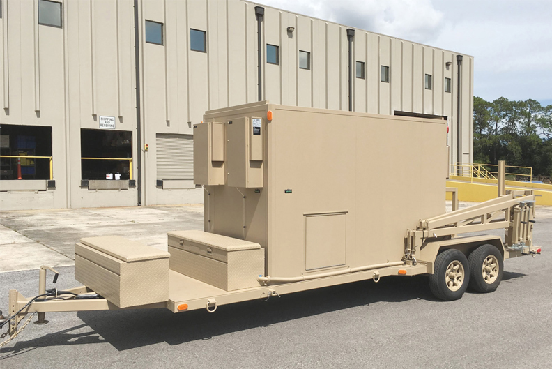 Beige security and communications mobile trailer in front of IMP building