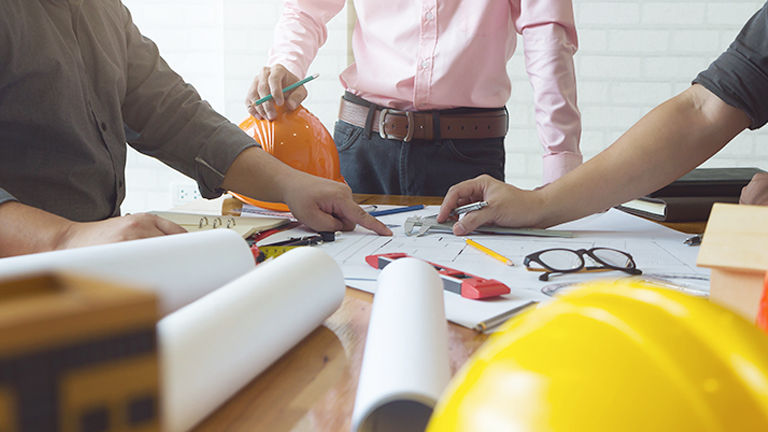 Three contractors discussing product plans on paper