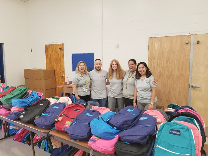 Employees in front of backpack donations